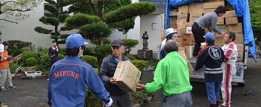 トラックの荷台に積まれた支援物資を下ろす被災地の人々