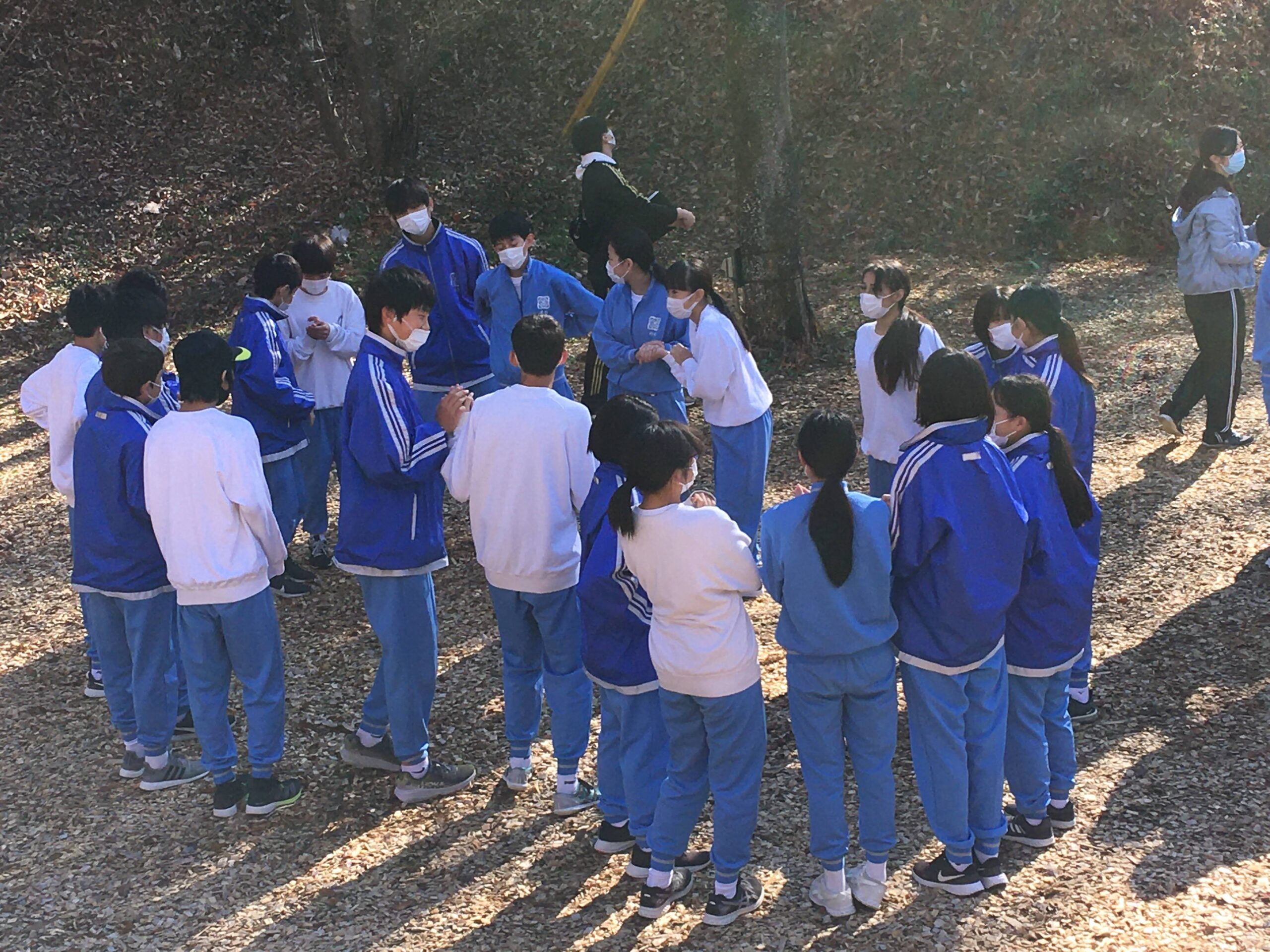 森の中で１ヶ所に集まって話をする生徒たち
