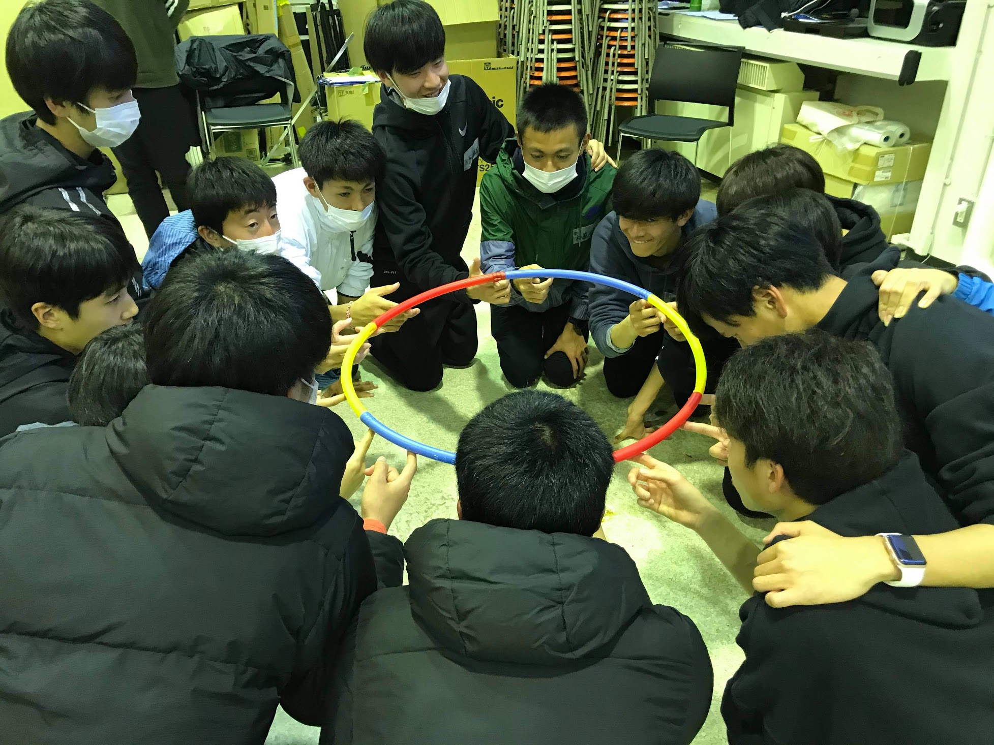 円になってフラフープを指に乗せる生徒たち