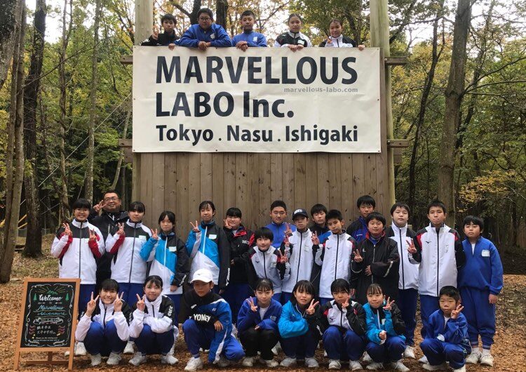 「MARVELLOUS LABO」の旗を取り付けた木製の壁の前に整列する参加者たち（栃木市立大平中学校02）