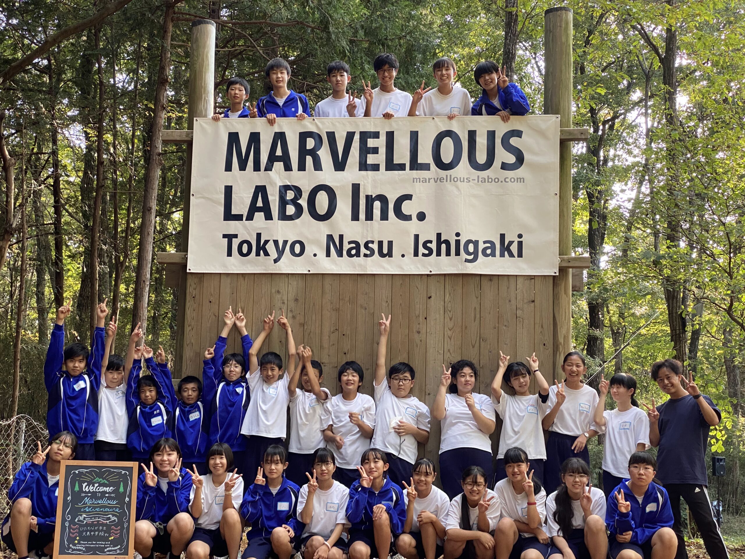 「MARVELLOUS LABO」の旗を取り付けた木製の壁の前に整列する参加者たち（ひたちなか市立大島中学校）